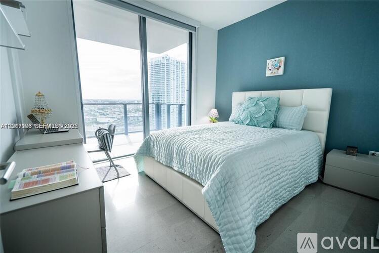 A bedroom with a large bed and a chair by the window.