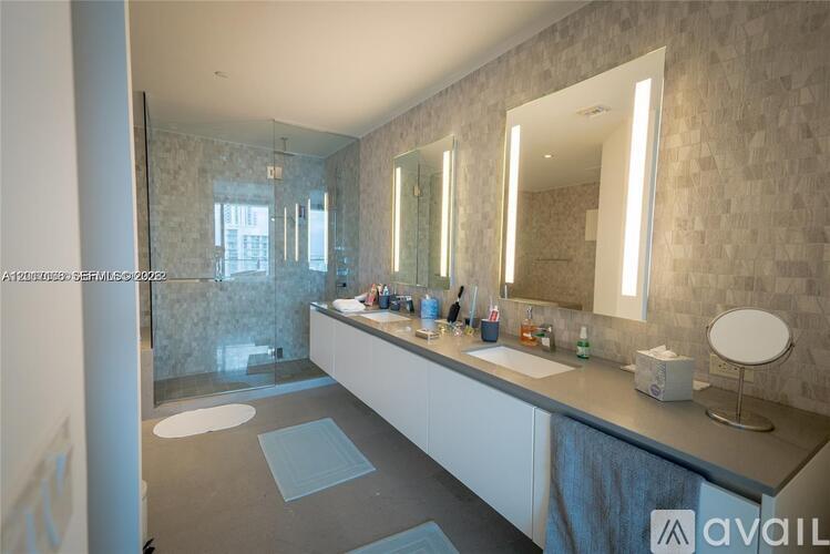 A bathroom with a vanity, mirrors, and a shower.