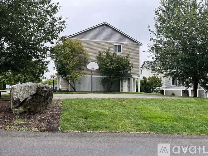 A house with a basketball hoop in the front yard.