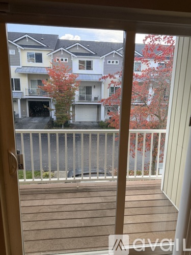 A view from a doorway looking out to a balcony with a tree and apartment buildings in the background.