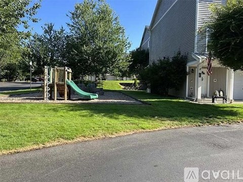 A playground with a green slide is located in front of a building.