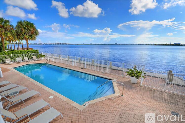A pool with lounge chairs and a view of the water.