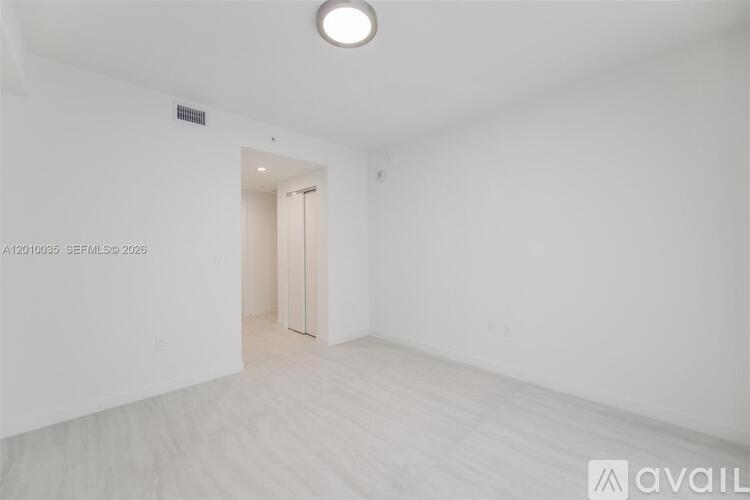 A white room with a door and a light on the ceiling.