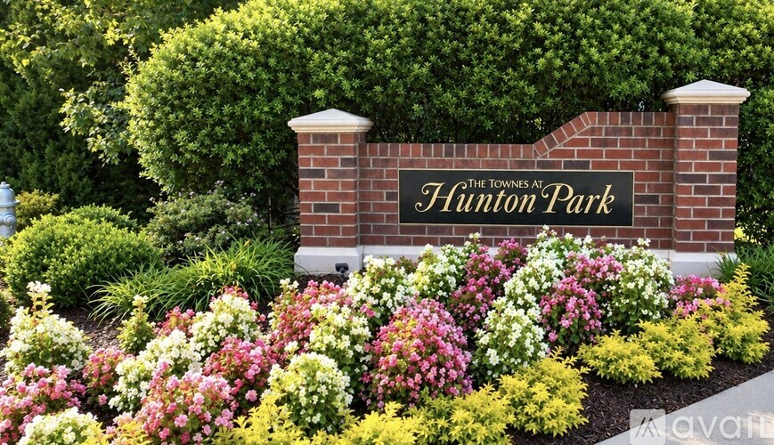 A sign that says "The Townes at Hunton Park" is in front of a hedge.