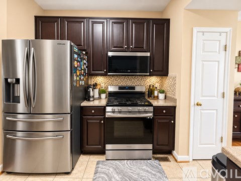 A kitchen with a stainless steel refrigerator and oven, brown cabinets, and a tile backsplash.