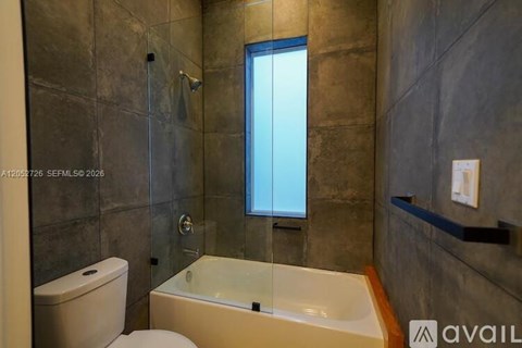 A bathroom with a toilet, a bathtub, and a window.