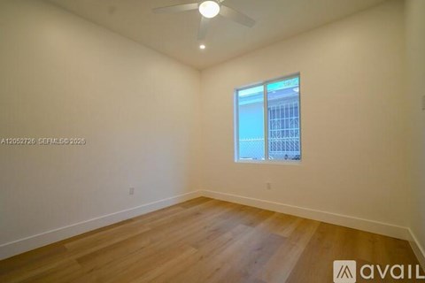 A room with wooden flooring and a window showing a building outside.