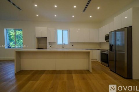 A modern kitchen with wooden floors and stainless steel appliances.