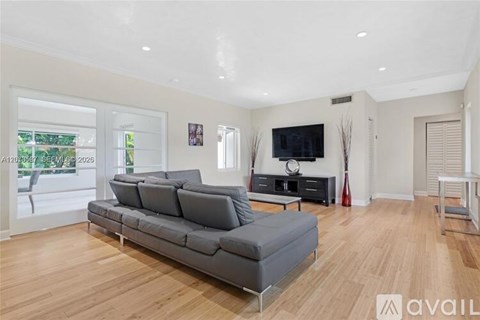 A living room with a grey sofa and a television on the wall.