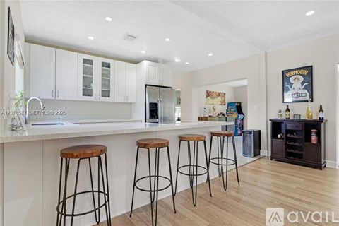 A kitchen with white cabinets and a bar area with stools.
