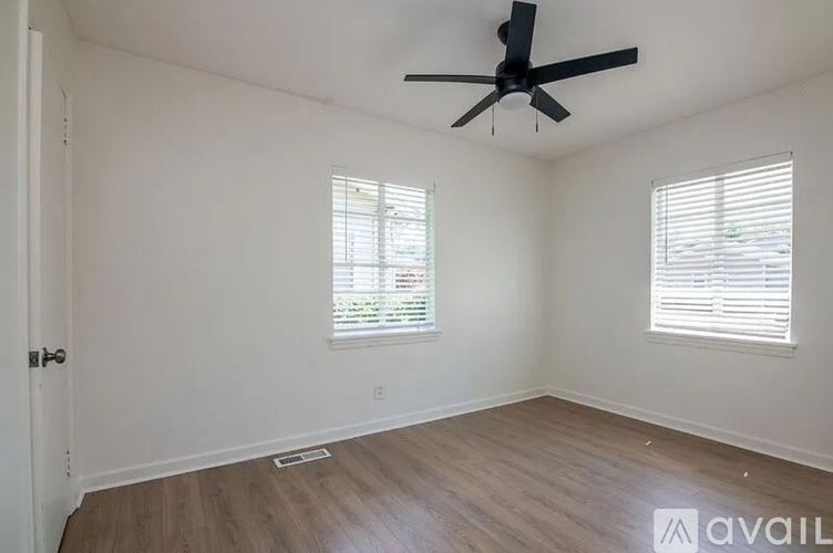 A room with a ceiling fan and two windows.