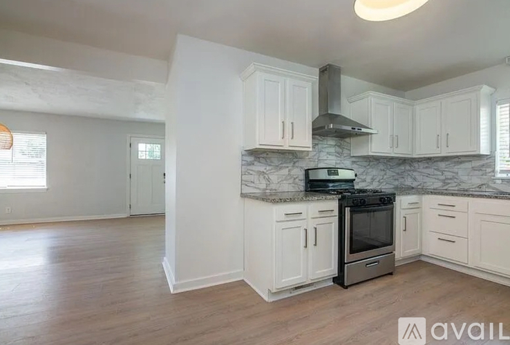 A kitchen with white cabinets and a marble countertop.