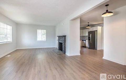A spacious living room with wood flooring and a fireplace.