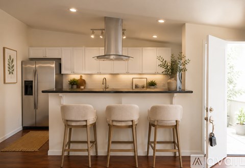 A kitchen with white cabinets and a stainless steel refrigerator.