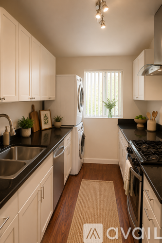 A kitchen with white cabinets and black countertops.