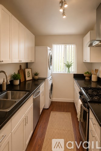 A kitchen with white cabinets and black countertops.