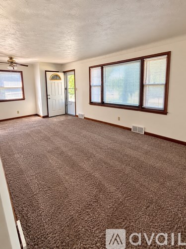 A room with brown carpet and a ceiling fan.