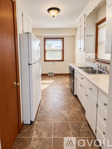 A kitchen with white cabinets and a brown door.