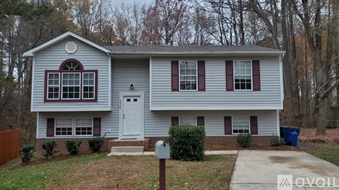 A two-story house with a white door and red shutters.