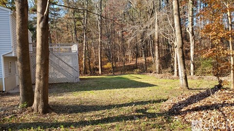 A white fence stands in a grassy field with trees in the background.