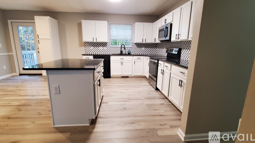 A kitchen with white cabinets and a black countertop.