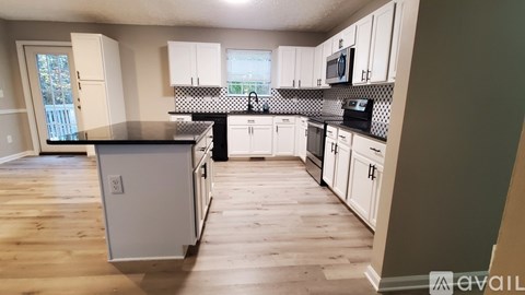 A kitchen with white cabinets and a black countertop.