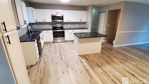 A kitchen with wooden floors and a black countertop.