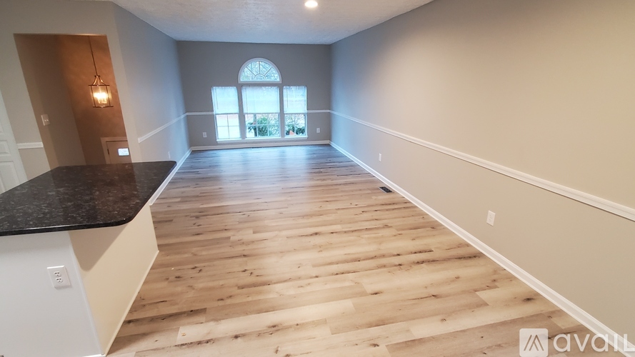 A spacious room with wooden flooring and a large window.