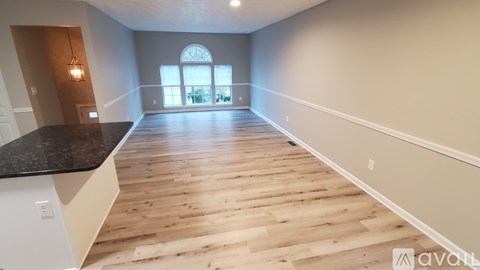 A spacious room with wooden flooring and a large window.