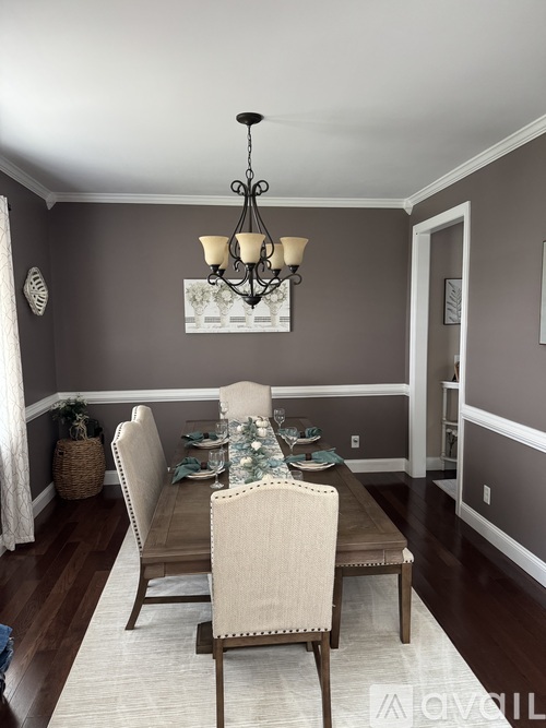 A dining room with a table set for two and a chandelier hanging from the ceiling.