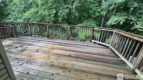 A wooden deck with a railing and trees in the background.