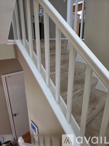 A staircase with a white railing and beige carpeted steps.