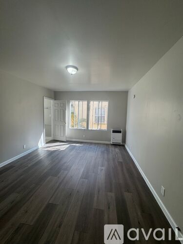 A room with wooden floors and a window with blinds.