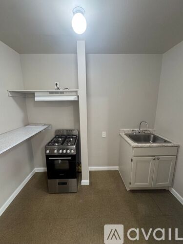 A small kitchen with a sink, stove, and shelves.