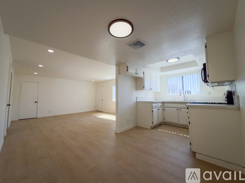A spacious room with wooden flooring and white walls.