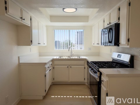 A kitchen with white cabinets and black appliances.