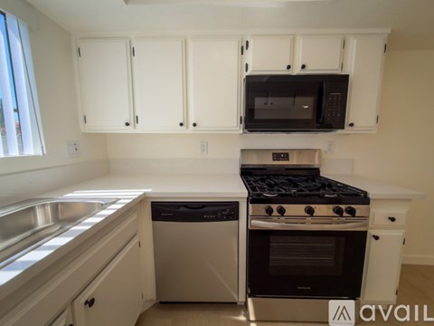A kitchen with white cabinets and a black microwave above the stove.