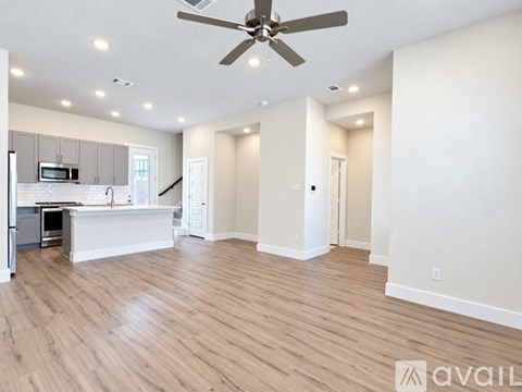 A spacious living room with a kitchen area in the background.