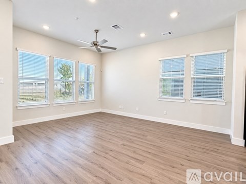 A spacious room with a ceiling fan and large windows.