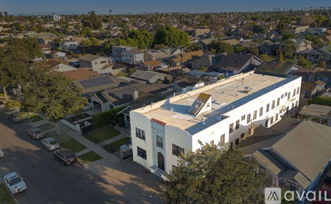 A white building with a brown roof is in the center of a residential area.
