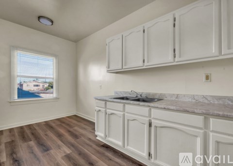 A kitchen with white cabinets and a marble countertop.