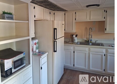 A kitchen with white cabinets and a black refrigerator.