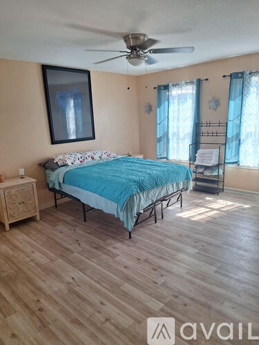A bedroom with a bed, dresser, and a ceiling fan.