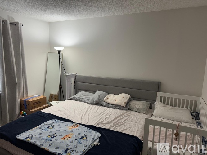 A bedroom with a bed, a lamp, and a nightstand.