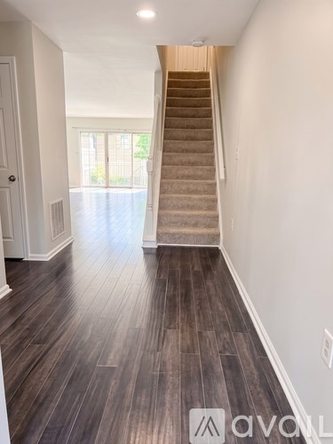 A hallway with wooden floors and a staircase leading to a second floor.