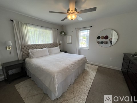 A bedroom with a large bed and a ceiling fan.