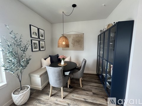 A dining area with a table set for two, a sofa, and a potted plant.