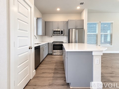 A modern kitchen with a white island and stainless steel appliances.