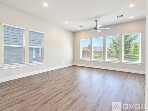 A spacious room with wooden flooring and a ceiling fan.