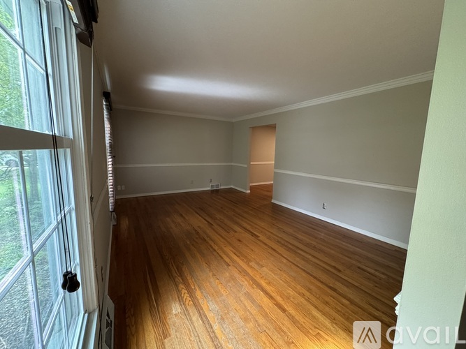 A room with wooden flooring and a window on the left side.